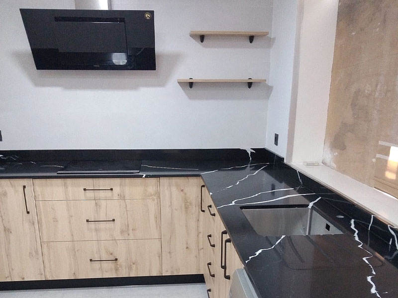Cocina de color roble y encimera negra con electrodomésticos encastrados