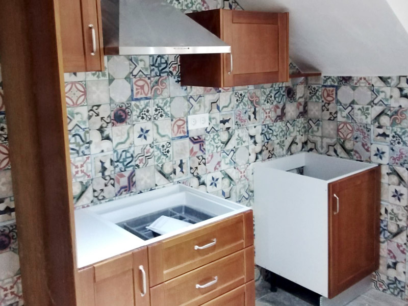 Cocina abuhardillada compuesta de una península y muebles clásicos